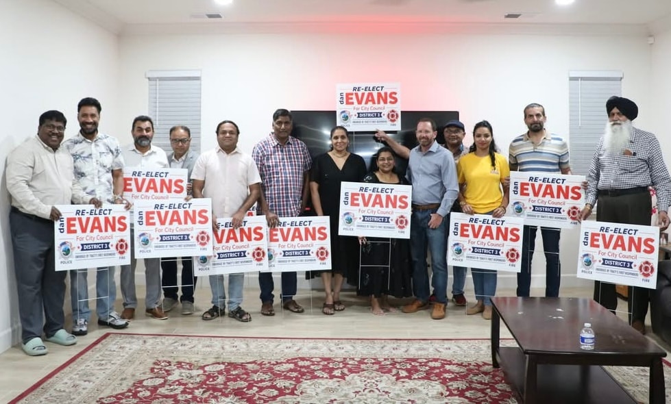 Community supporters holding Re-Elect Evans signs at indoor rally